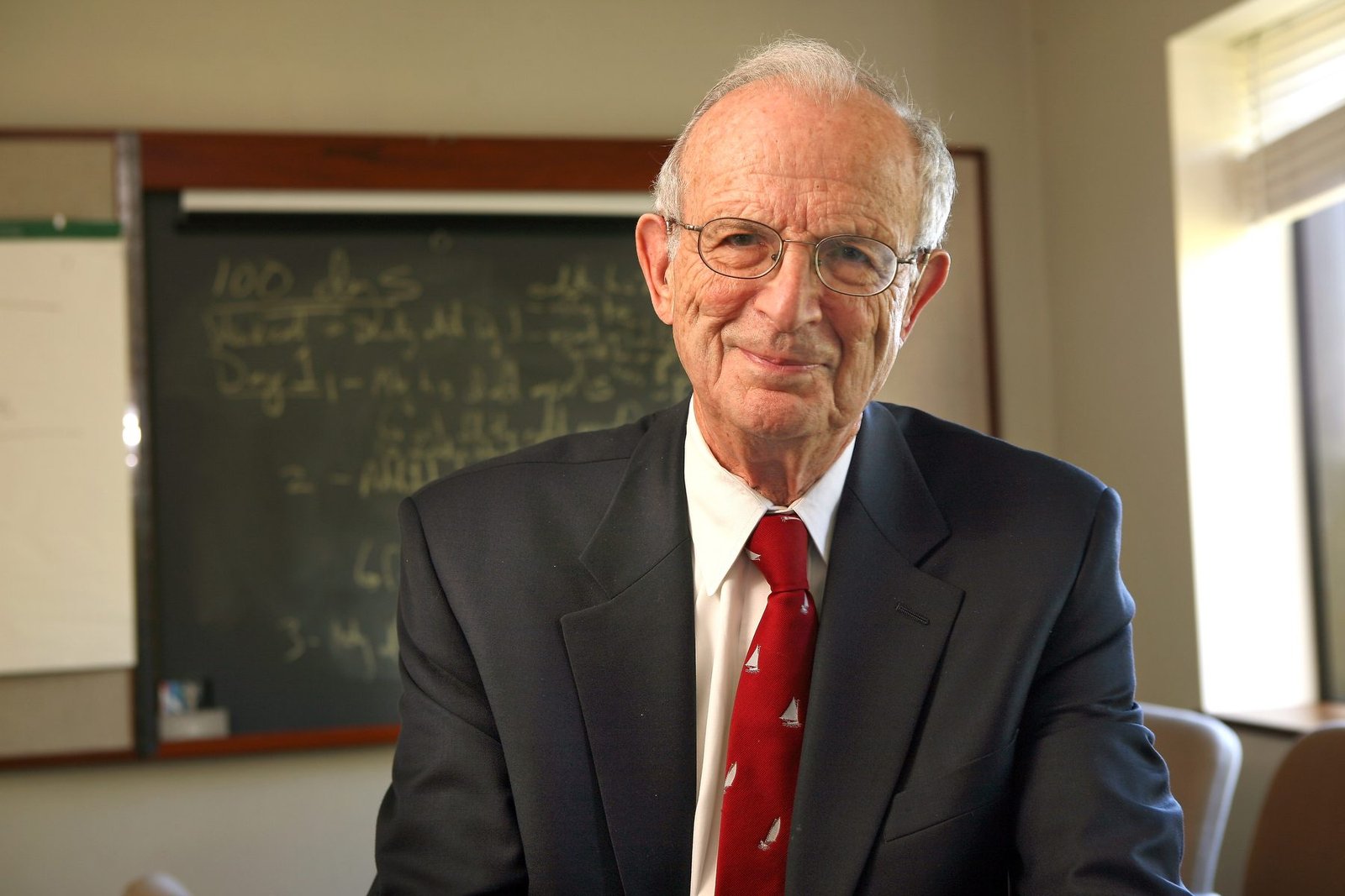 Professor Ray Goldberg seated in front of a chalkboard